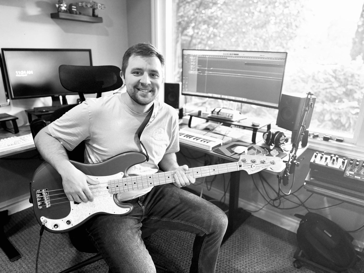 Jesse recording the Thread soundtrack in his home studio, holding a bass guitar with a DAW session open behind him